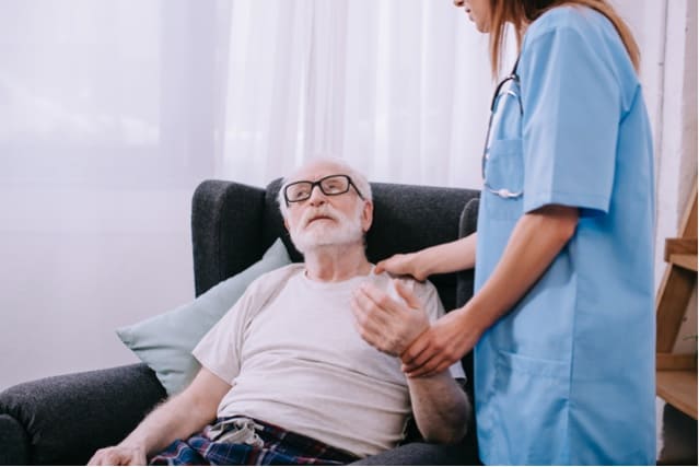Nurse checking heart rate of elderly man