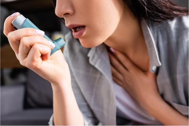 Woman holding asthma inhaler.