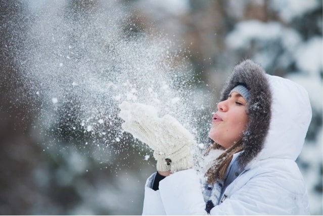 Woman blowing on snow.