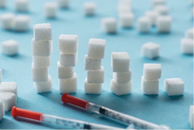 Stacked sugar cubes and insulin syringes.