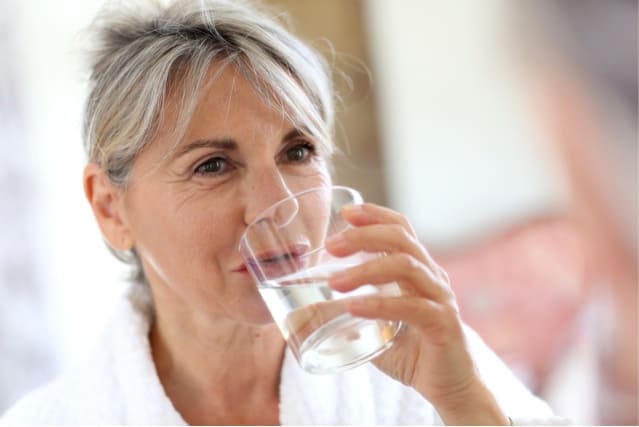 Senior woman drinking water.
