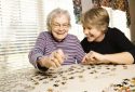 Elderly woman and young woman doing a puzzle.