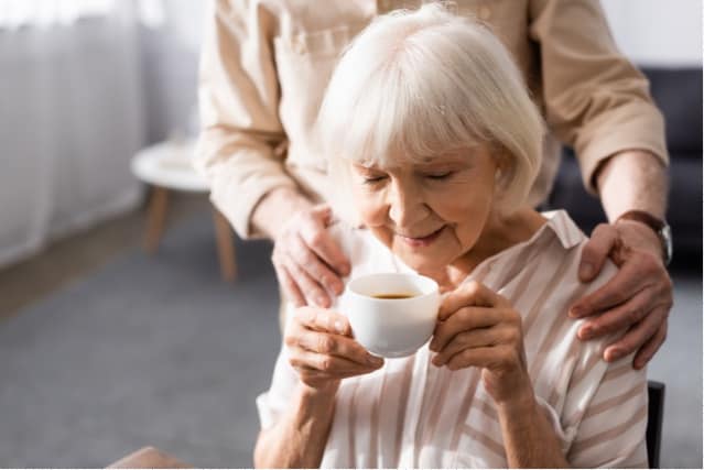 Elderly woman sipping coffee.