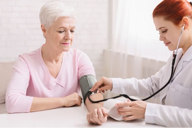 Doctor checking blood pressure of elderly woman.