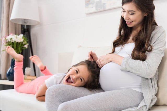 Pregnant woman with daughter lying in lap.