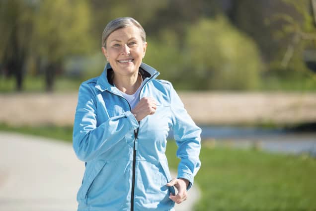 Older woman jogging in park.