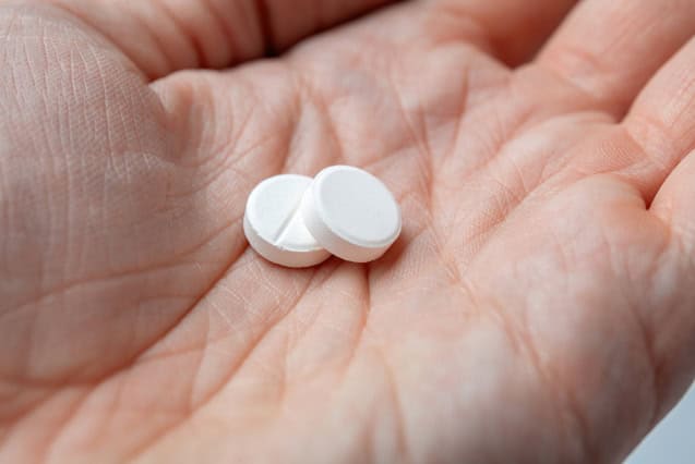 Two white pills in hand.