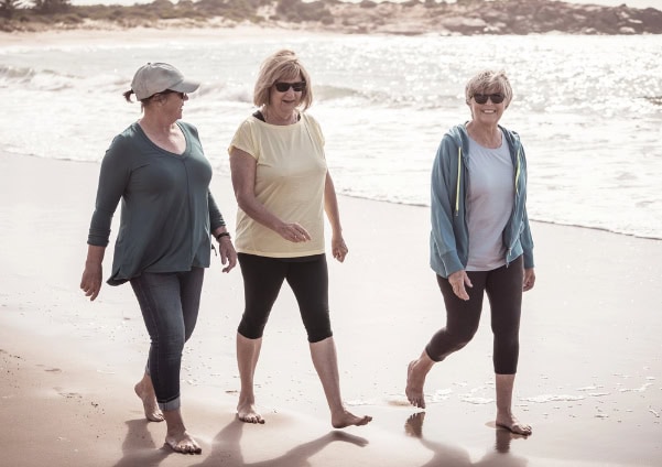 Group of older women walking on the beach.