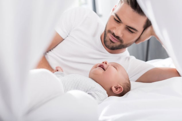 Father lying in bed with baby.