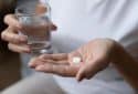Older adult taking pill.