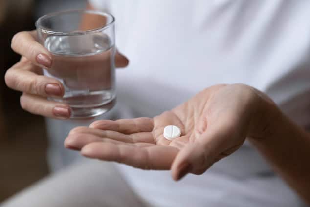 Older adult taking pill.