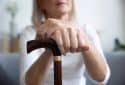 Older woman holding a walking stick.