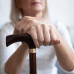Older woman holding a walking stick.