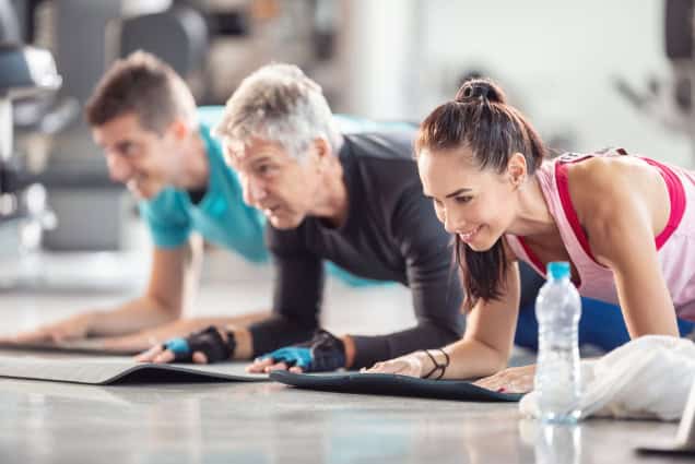 Adults doing elbow planks in gym (isometric exercise).