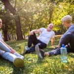 Senior couple and young female instructor exercising outdoors.