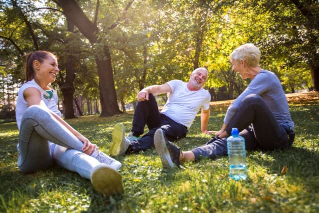 Senior couple and young female instructor exercising outdoors.